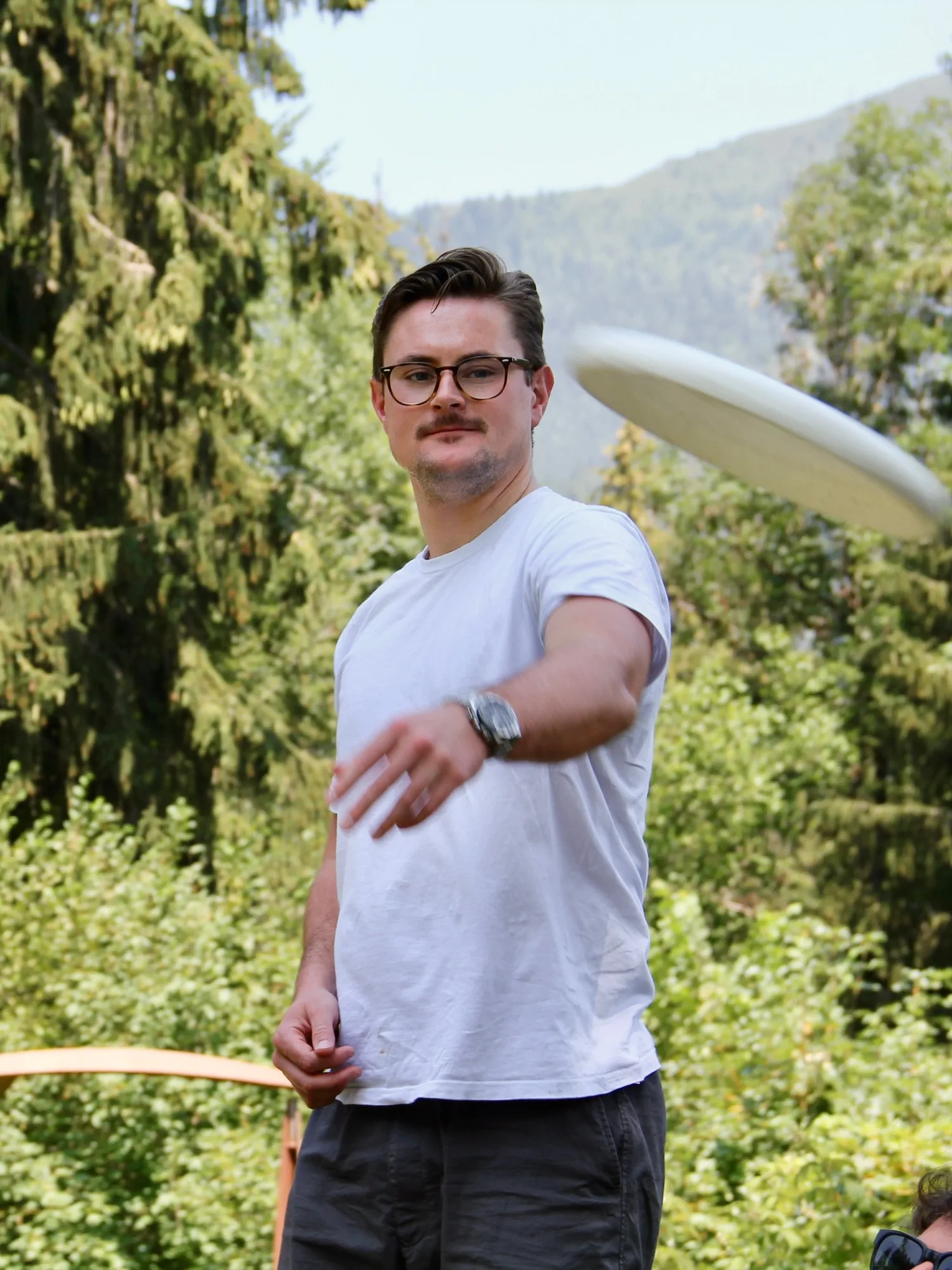 Lennart Böhm throwing a frisbee outdoors during a break at the Les Houches School of Physics, mountains in the background.