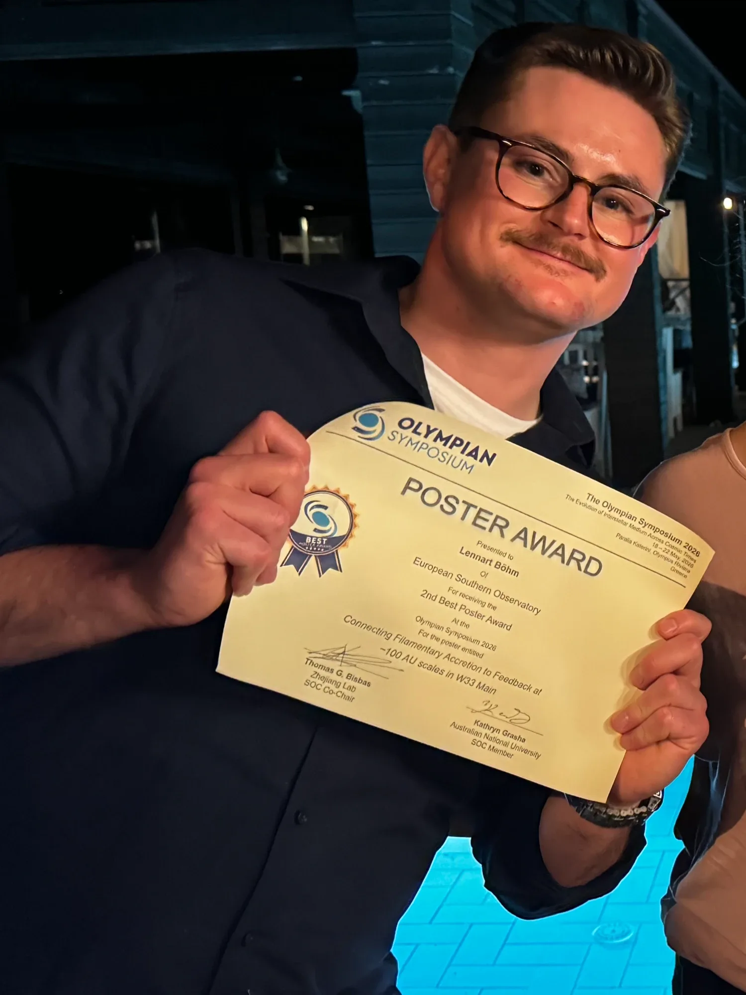 Lennart Böhm holding a certificate for the 2nd Best Poster Award at the Olympian Symposium 2026.